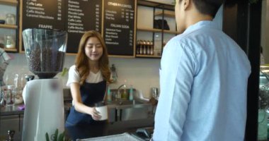 Müşteri kahve dükkanında sıcak içecek almak için e-ödemeyi cep telefonuyla yapıyor.