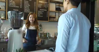 Müşteri kahve dükkanında sıcak içecek almak için e-ödemeyi cep telefonuyla yapıyor.