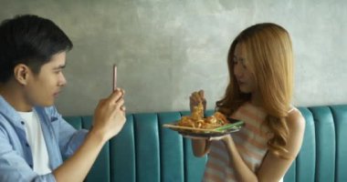 Genç Asyalı turistler Tayland 'da Pad Thai veya Tayland eriştesi yemekten ve cep telefonuyla selfie çekmekten zevk alır..
