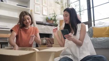 İki genç Asyalı kadın kutuya bir şeyler koydu ve kutuyu kapatmadan önce listeyi telefonlarıyla kontrol etti..