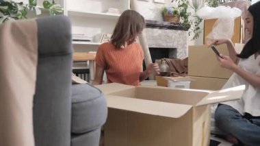 İki genç Asyalı kadın kutuya bir şeyler koydu ve kutuyu kapatmadan önce listeyi telefonlarıyla kontrol etti..