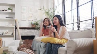 Kanepede oturan iki genç Asyalı kadın evlerini nasıl düzenleyeceklerini konuşuyorlar..