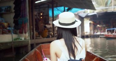 Genç Asyalı turist neşeli ve mutlu görünüyor Damnoen Saduak yüzen Market Tayland kanalı boyunca tekne ile seyahat görmek.