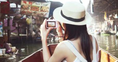 Genç Asyalı turist neşeli ve mutlu görünüyor Damnoen Saduak yüzen Market Tayland kanalı boyunca tekne ile seyahat görmek.