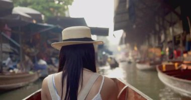 Genç Asyalı turist neşeli ve mutlu görünüyor Damnoen Saduak yüzen Market Tayland kanalı boyunca tekne ile seyahat görmek.