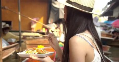 Genç Asyalı kadın turist fotoğraf çekip gülümsüyor Damnoen Saduak yüzen marketi Tayland kanalı boyunca tekneyle seyahat ediyor.