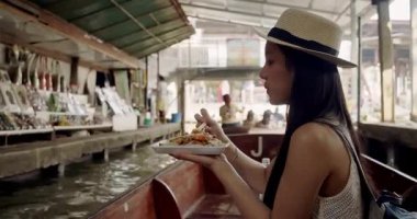 Genç Asyalı kadın turist fotoğraf çekip gülümsüyor Damnoen Saduak yüzen marketi Tayland kanalı boyunca tekneyle seyahat ediyor.