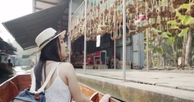 Genç Asyalı kadın turist fotoğraf çekip gülümsüyor Damnoen Saduak yüzen marketi Tayland kanalı boyunca tekneyle seyahat ediyor.