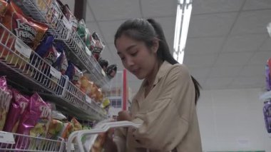 Müşteri dükkandaki alışveriş arabasına ürün ekliyor.