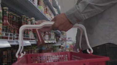 Müşteri dükkandaki alışveriş arabasına ürün ekliyor.