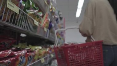 Müşteri dükkandaki alışveriş arabasına ürün ekliyor.
