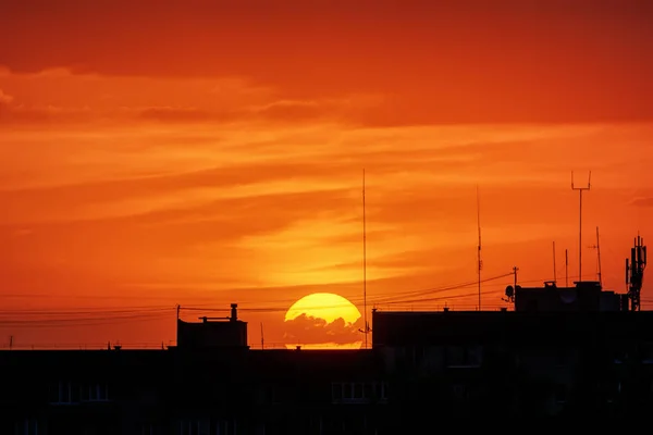 街の屋根のシルエットを背景に日没時に雲と空 — ストック写真