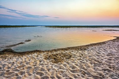 Gölün kumlu kıyısında gün doğumu.