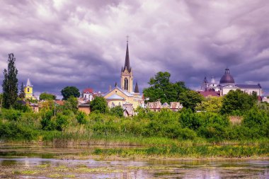 Yaz manzarası - kilise, tapınak ve güneşli bir günde park olan nehir kıyısı (Lutsk, Ukrayna).
