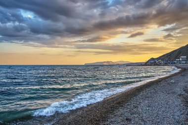 Gün batımında deniz kıyısında çakıl taşı plajı.