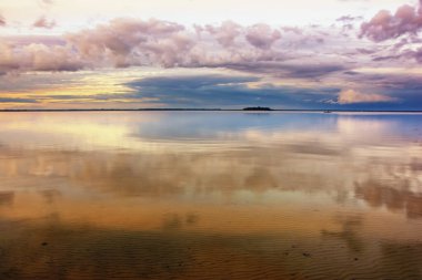 Gölde gün batımı - fırtına bulutları sakin suya yansıyor.