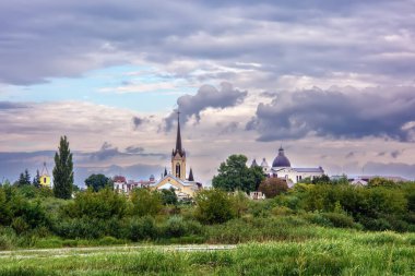 Yaz manzarası - kiliseleri, tapınakları ve bulutlu bir günde parkı olan nehir kıyısı (Lutsk, Ukrayna).
