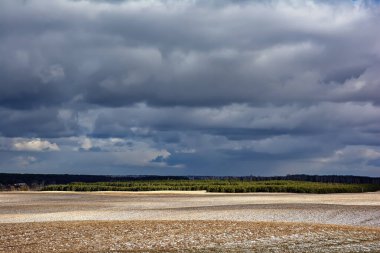 Kış manzarası - karla kaplı tarlalar üzerinde fırtına bulutları.