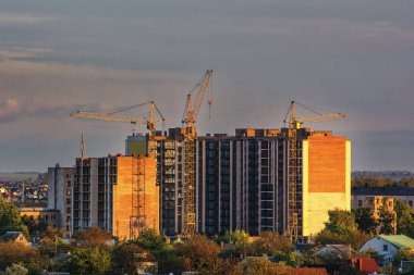 Gün batımında kule vinçleriyle yüksek binaların inşası.
