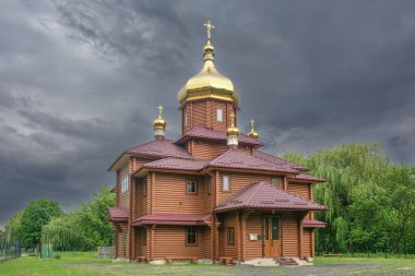 Lutsk (Ukrayna) şehrindeki Ortodoks ahşap kilisesi fırtına bulutlarının arka planında sağanak öncesi.