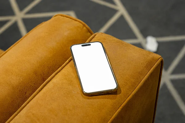 Çalışan masa ve deri koltukta parola sayfası olan cep telefonu.