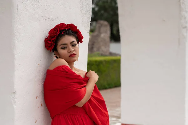 Frida-Inspired Essence: A Mexican woman, reminiscent of Frida Kahlo, graces an aged chair beneath delicate archways. Bathed in a play of light and shadow, her traditional attire and contemplative gaze