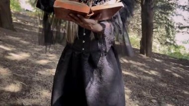 Fantezi cadılar bayramı kadını modern cadı yanan mumlar çemberinde karanlık odada oturuyor. Bayan Büyücü ritüel dansı yapıyor, kitap yakıyor. Siyah elbiseli karanlık gotik kraliçe kız. 4k