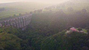 Meksika 'nın Tepotzotlan eyaletinde bulutlu gökyüzü ile gün doğumunda dağlar arasında su kemeri