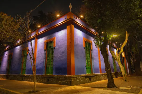 Koyu mavi duvarlar, sıcak aydınlatma ve yeşil pencere çubukları ikonik sömürgeci mimarinin altını çiziyor. Mavi ev un coyoacan