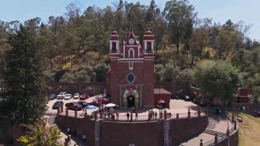 Meksika Metepec 'teki Calvary Kilisesi' nin görkemli bir şekilde tepenin üzerinde durduğu dinamik bir zaman dilimi. Dizide ayrıca geleneksel büfe ve ünlü Denizkızı Çeşmesi 'nin sembolleri olan pitoresk ana plazayı da gözler önüne seriliyor.