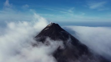 Guatemala Fuego Volkanı 'nın yoğun bulut örtüsünün içinden yükselen ve zirveden yükselen dumanla birlikte dramatik ve güçlü bir doğa yoğunluğu görüntüsü sunan sinematik dron görüntüleri..