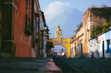 Antigua Guatemala 'daki Santa Catalina Kemeri' nin manzarası. Arka planda kısmen bulutlarla kaplı bir volkan bölgenin kültürel ve doğal güzelliğini temsil ediyor..