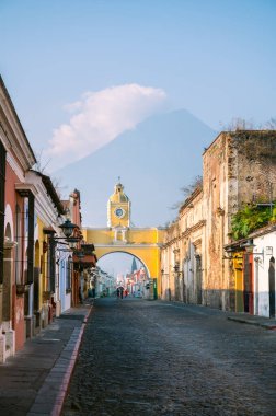 Antigua Guatemala 'daki ikonik Santa Catalina Kemeri' nin manzarası. Arka planda volkan var. Koloni binaları ve canlı renkler şehrin kültürel cazibesini yansıtıyor..