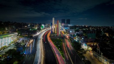 Estado de Mexico 'daki ikonik Torres de Satelite' in canlı gece görüntüsü. Uzun pozlar sonucunda parlak neon ışıkları, aydınlık gökyüzü ve renkli trafik ışıkları....