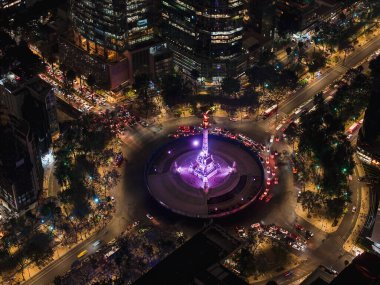 Paseo de la Reforma boyunca trafik ve ışıklarla çevrili Mexico City 'nin ikonik Bağımsızlık Meleği anıtının çarpıcı bir görüntüsü. Canlı ve dinamik bir şehir manzarası.