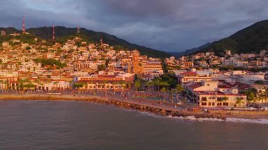 Sıcak altın ışıkla aydınlatılmış. Geleneksel kemerleri, küçük amfi tiyatrosu ve deniz kenarında yürüyen insanların hareketli atmosferiyle Pasifik Okyanusu ve etrafındaki dağların çarpıcı manzarasıyla harmanlanmış sahil yürüyüşü..