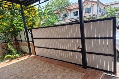 Large iron fence gate in front of the house, fence on the side of the road