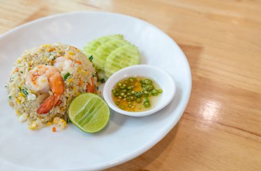 Prawn fried rice on a white plate placed on wooden table background