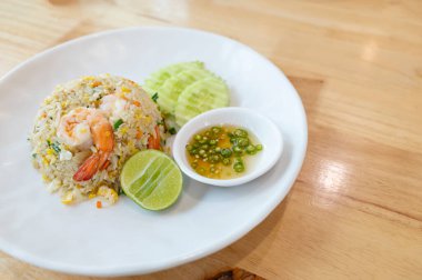 Prawn fried rice on a white plate placed on wooden table background