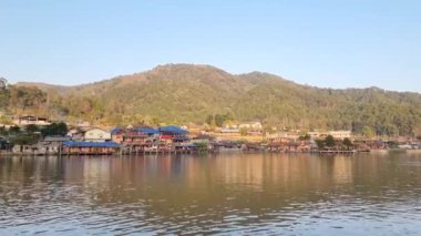 Ban Rak Thai, Mae Hong Son, Tayland -23 Ocak 2022: Turistler gölü görmek için tekneyle gezerler ve suyun üzerinde yüzen sisli ve güzel huzurlu köy Ban Rak Thai, Mae Hong Son, kuzey Tayland.