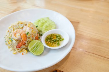 Prawn fried rice on a white plate placed on wooden table background