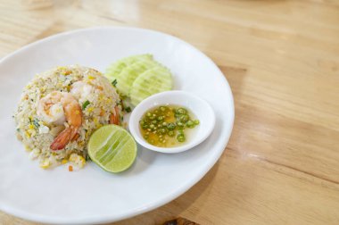 Prawn fried rice on a white plate placed on wooden table background