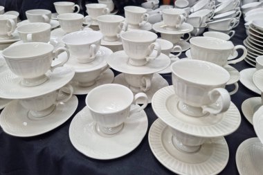 Siyah arka planda beyaz terracotta kahve kupaları satan bir dükkan..