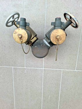 Soyut duvar kağıdı arka planındaki bir binanın duvarında eski bir yangın musluğu var.