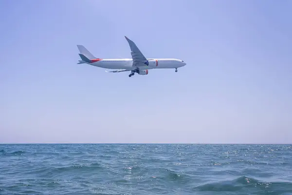 低空飞行的飞机在蓝天的海面上即将着陆 图库照片