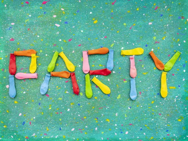 Word Party made of multi colored deflated balloons on abstract spotted background
