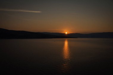 Denizin üzerinde gün doğumu, bulutsuz açık gökyüzü. Altın saat.