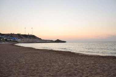 Ufukta canlı bir gün batımı beliriyor, altın rengi denizler, küçük dalgalar yavaşça kumlara değiyor.,