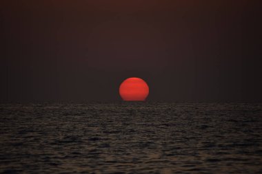 Ufukta canlı bir gün batımı beliriyor, altın rengi denizler, küçük dalgalar yavaşça kumlara değiyor.,