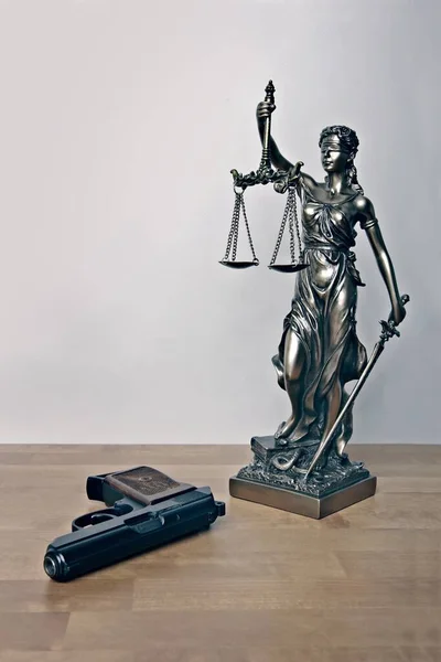 Δικαιοσύνη Μάτια Δεμένα Αγαλματίδιο Δίπλα Ένα Όπλο Στο Τραπέζι Κάθετη — Φωτογραφία Αρχείου